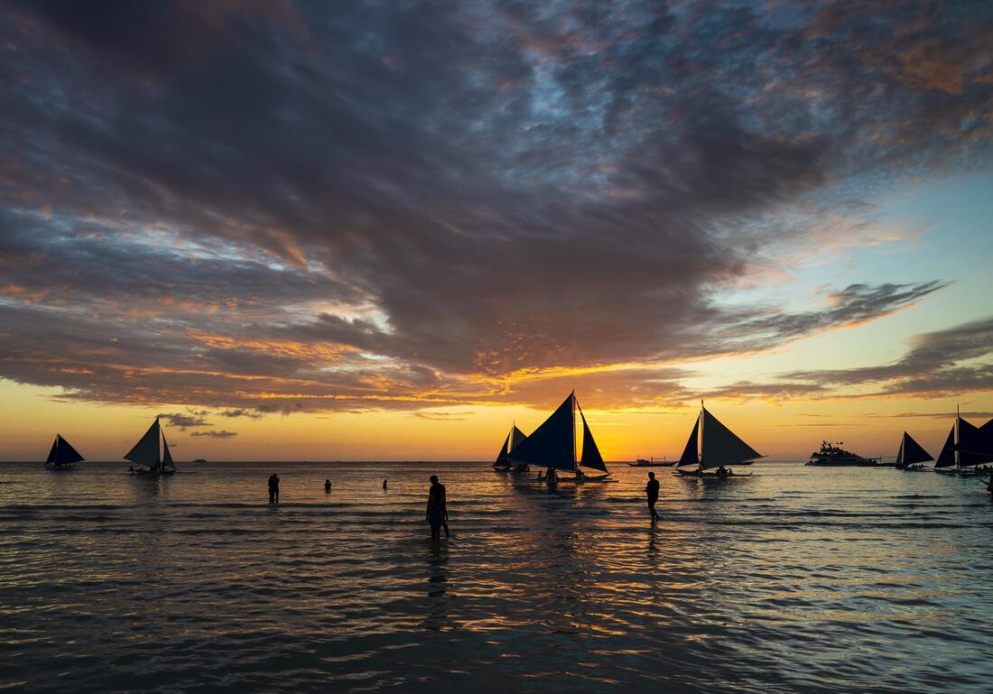 Sunset with sailing boats and tourists in Boracay Island Philippines