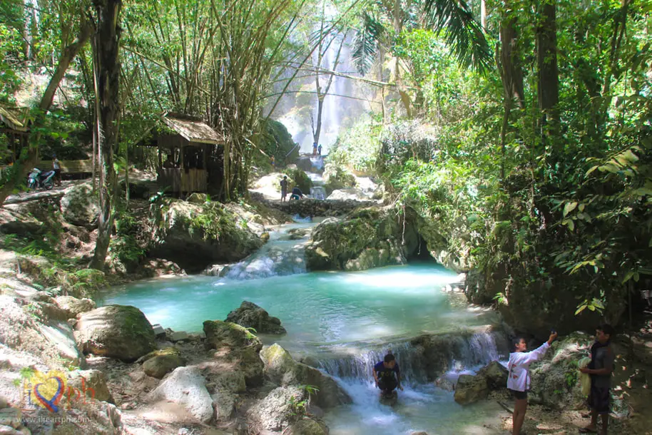 Bluish green water of Tumalog Falls plus lots of greeneries around it 