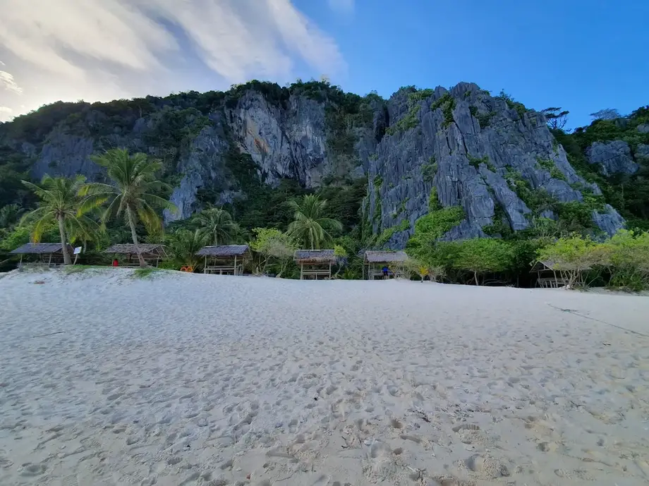 Dark limestone cliffs against the blue sky and lush coconut trees in Black Island in Coron Palawan Philippines